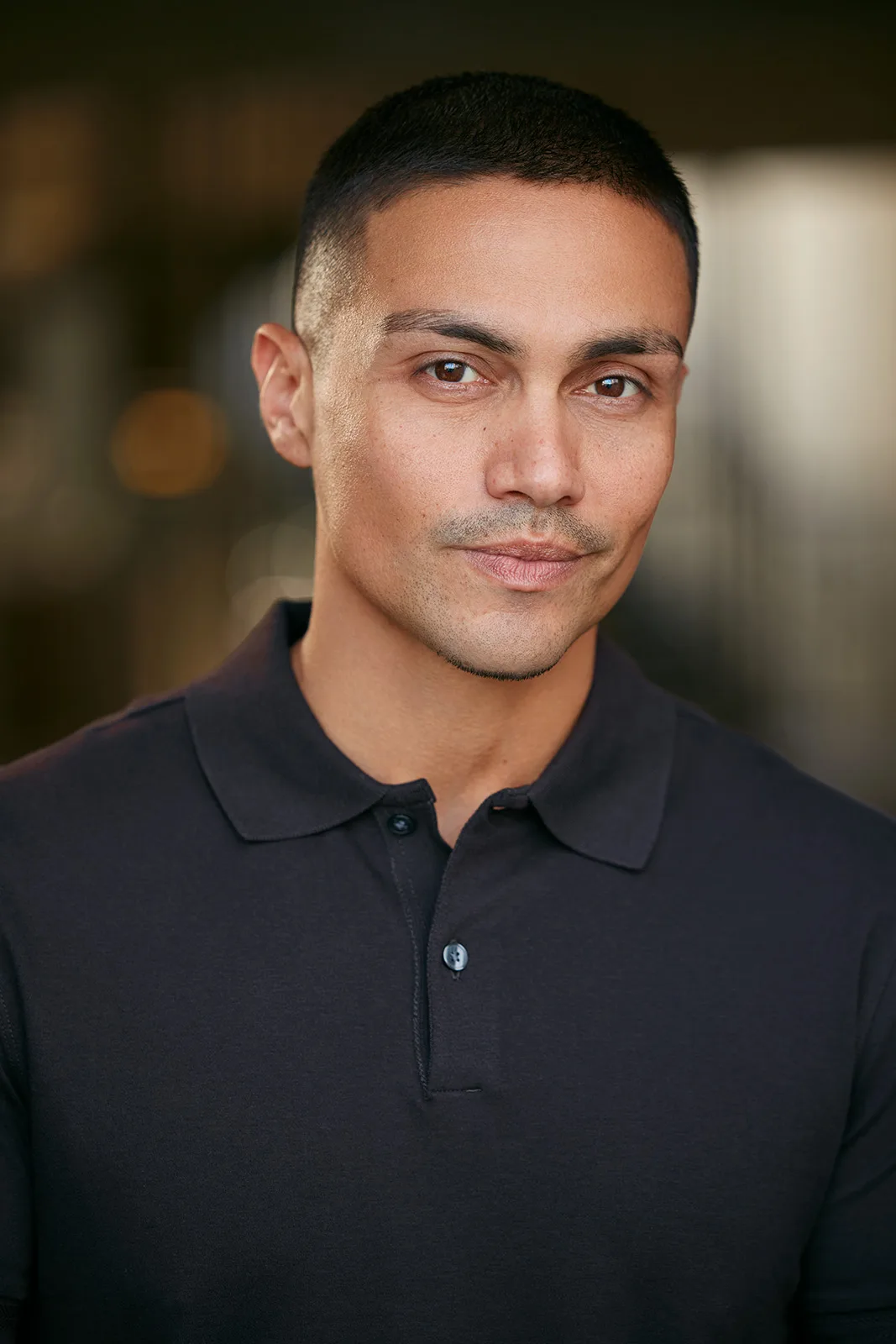 Rene Moran in a charcoal polo on a warm blurred background — celebrity headshot by Headshots LA in Los Angeles.